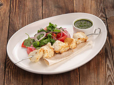 Spotted wolffish skewer. Served with tomatoes and chimichurri sauce